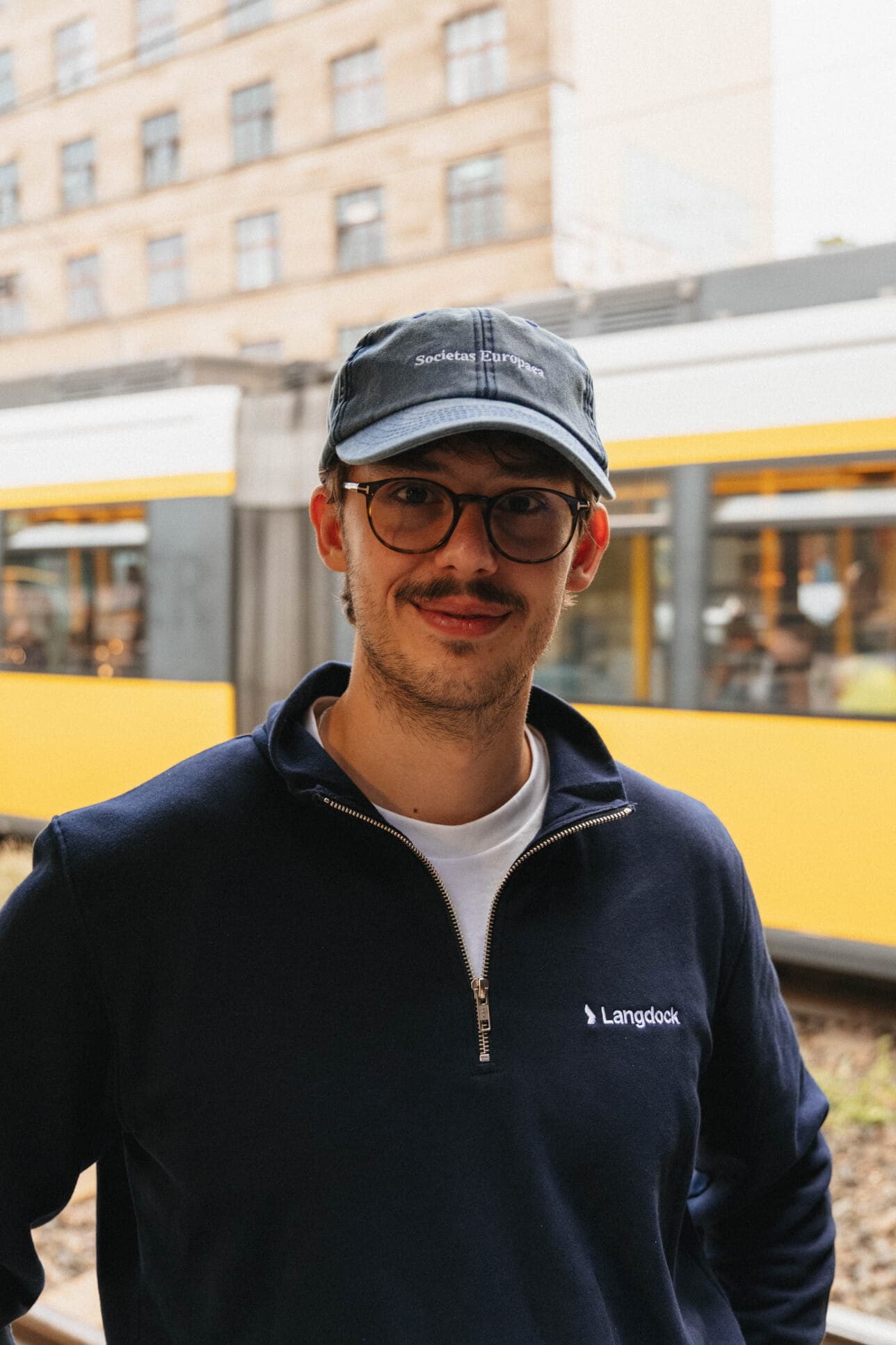 A teammate standing near a yellow Berlin tram.