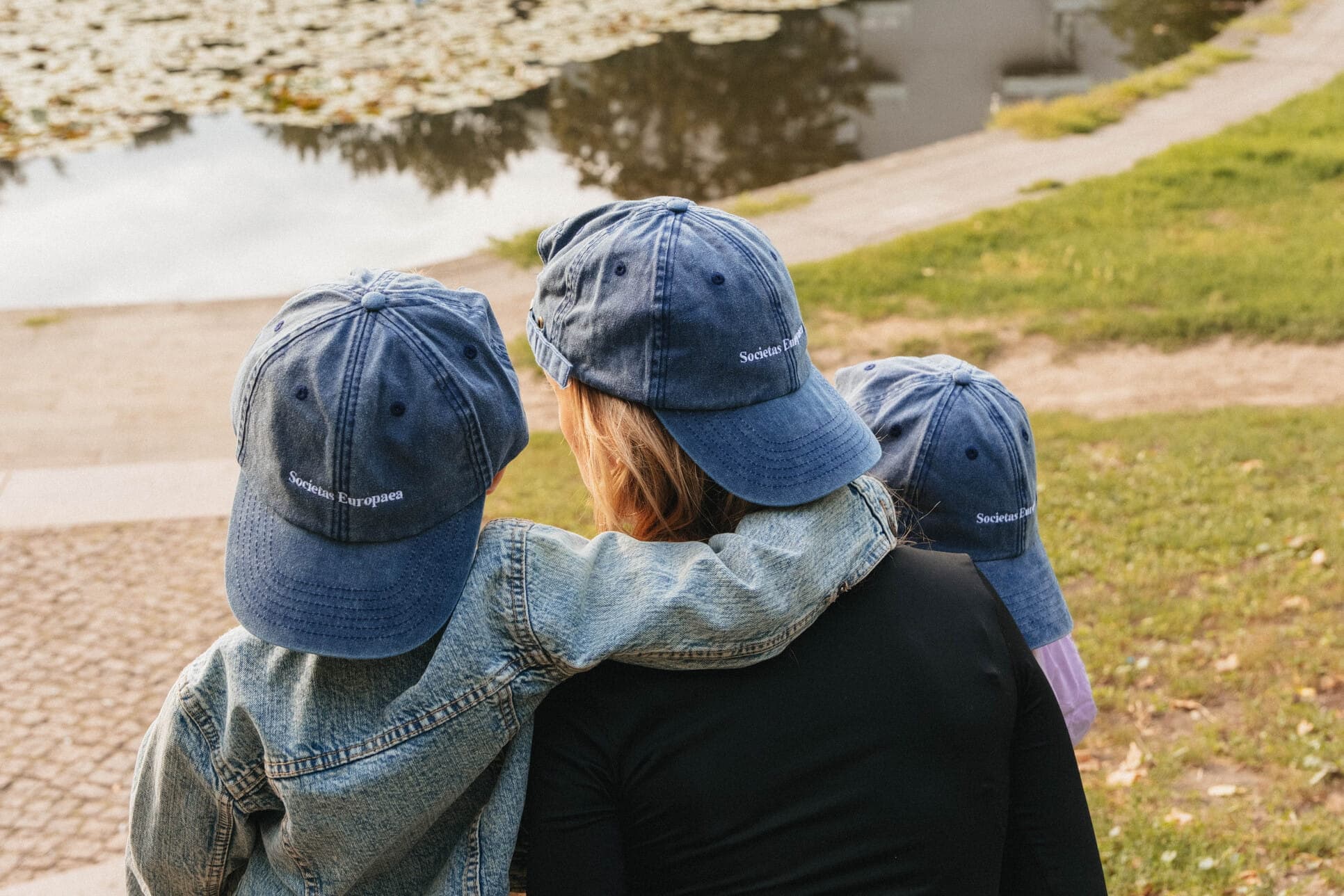 Friends in blue caps sitting beside the water.