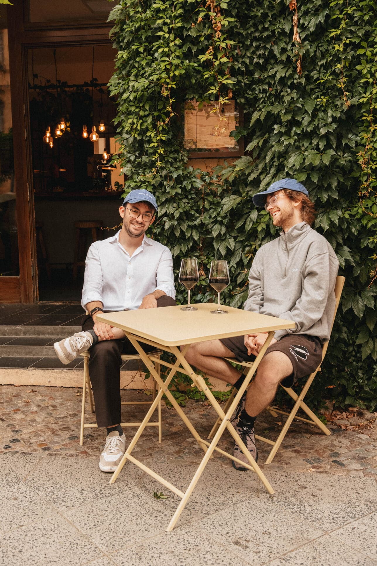 Two teammates having coffee at a sidewalk table.