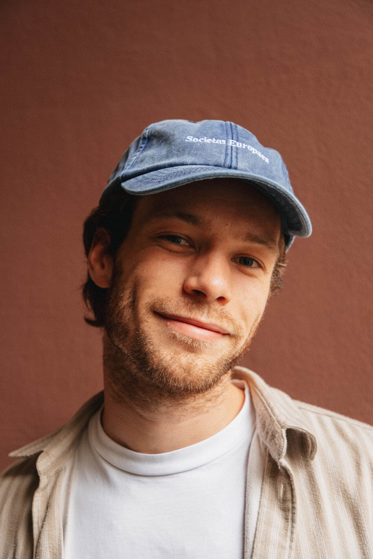A teammate in a blue cap beside a brick wall.
